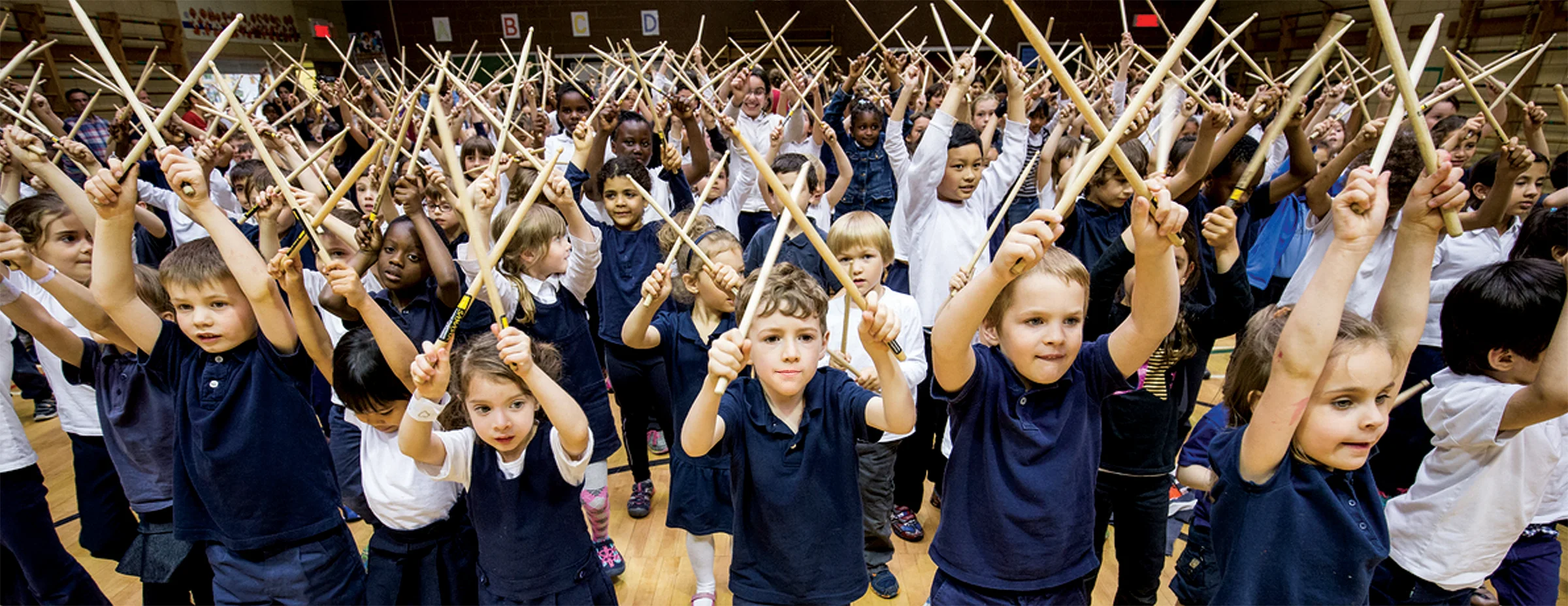 A large group of students raises their ClavSticks