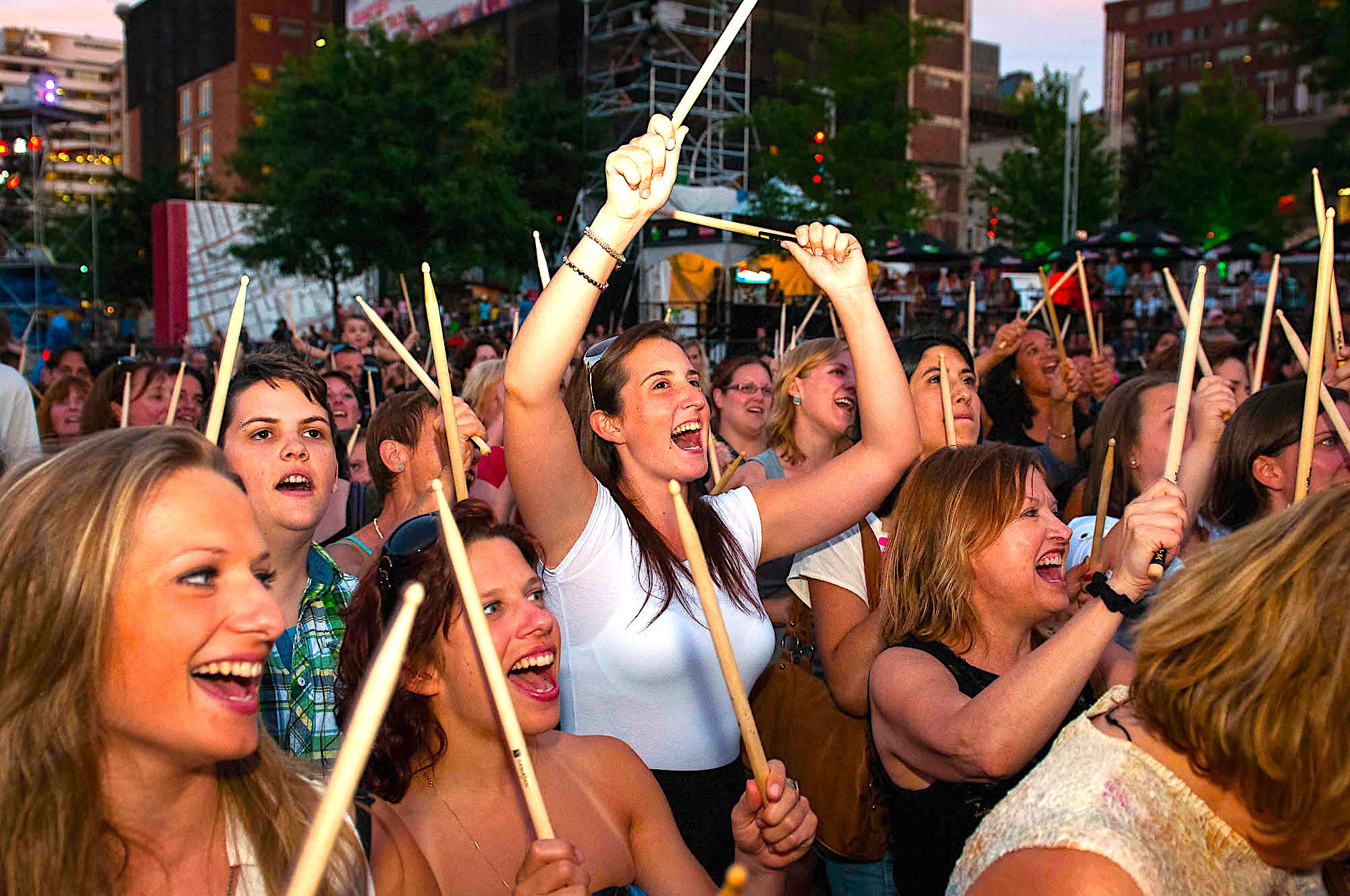 Public d’un festival extérieur participant au spectacle SAMAJAM avec des baguettes.